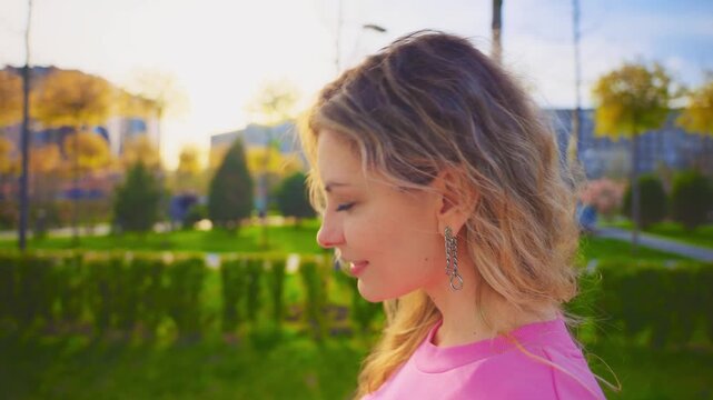 Portrait young beauty happy healthy woman woman sunbathing with natural vitamin D3 walking in street modern city blonde cyrly hair sexy adult girl smiling face. Spring nature green trees sun light sky