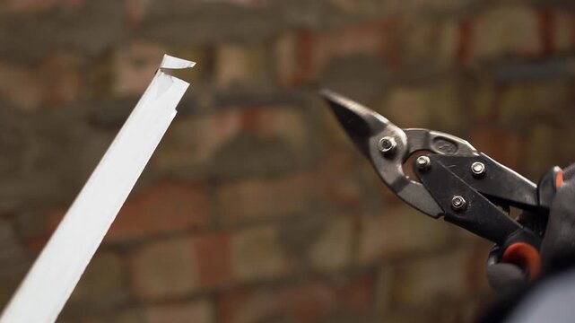 Cutting galvanized metal profile with snips during apartment renovation