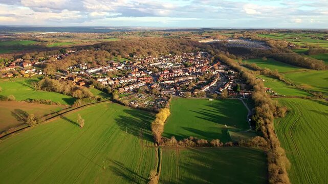 Aerial drone view of Baddesley Ensor village, featuring charming brick residential houses bathed in warm, golden light during sunset.