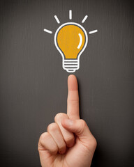  a hand pointing at a light bulb on a chalkboard background, representing the concept of a new idea or creative thinking