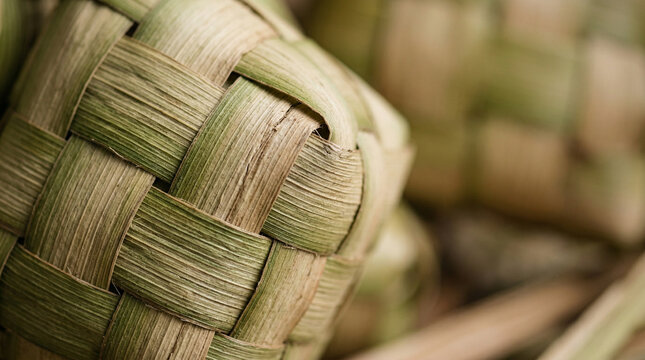 Extreme macro close up of woven palm leaves forming a traditional ketupat texture.