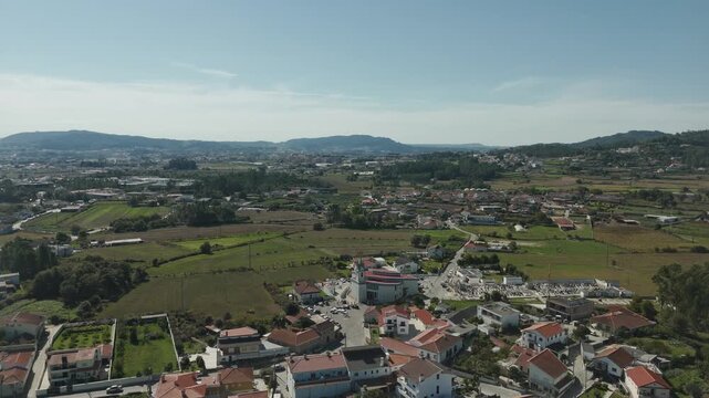 Drone aerial view of Igreja Paroquial de Lij&oacute; in Barcelos Portugal surrounded by rural landscape houses farmland and rolling hills under clear sky