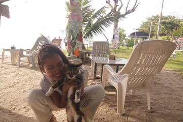 태국 해변 카페에서 고양이와 함께 여유로운 휴식을 즐기는 아름다운 태국 여성의 이국적인 라이프스타일
