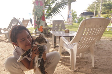 태국 해변 카페에서 고양이와 함께 여유로운 휴식을 즐기는 아름다운 태국 여성의 이국적인 라이프스타일
