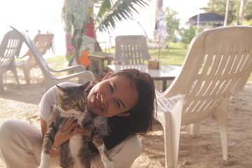 태국 해변 카페에서 고양이와 함께 여유로운 휴식을 즐기는 아름다운 태국 여성의 이국적인 라이프스타일
