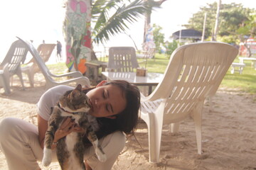 태국 해변 카페에서 고양이와 함께 여유로운 휴식을 즐기는 아름다운 태국 여성의 이국적인 라이프스타일
