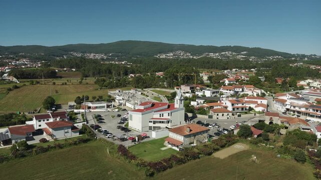 Drone aerial view of Igreja Paroquial de Lij&oacute; in Barcelos Portugal showing parish church cemetery village houses farmland and green hills in Minho region