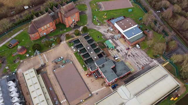 Top down aerial view of a sewage treatment plant featuring circular settling ponds and aeration tanks in the UK.