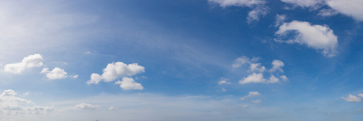 Peaceful daytime panorama sky with soft white clouds flowing in a deep blue atmosphere.