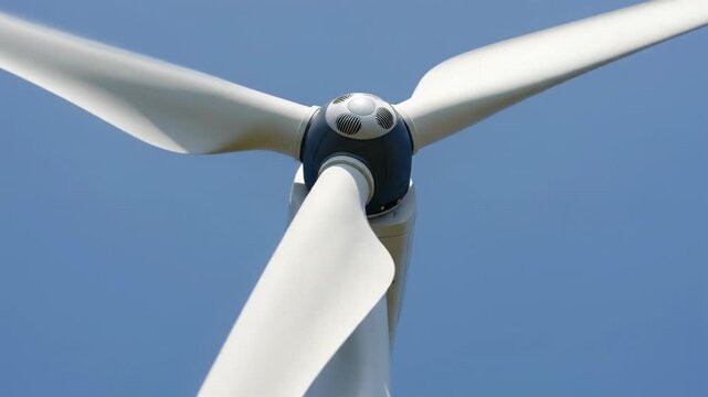 Close-up of a rotating wind turbine against a clear blue sky, clean energy generation