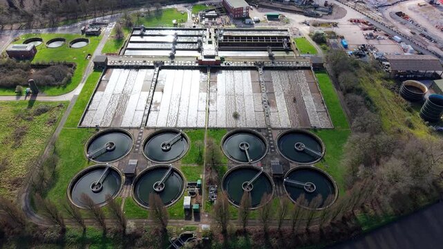 Aerial drone view of the massive Coleshill Sewage Treatment Works near Birmingham, featuring circular clarifier tanks and digestion ponds.