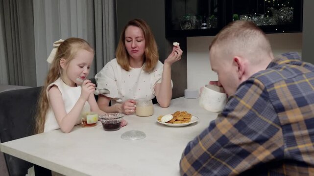 Loving family sharing morning meal, parents and daughter sitting at home dining table, enjoying warm breakfast and genuine connection with tender interaction