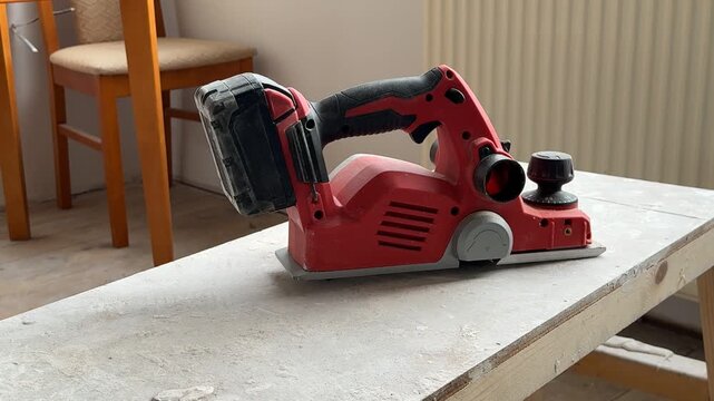 A still shot of a power planer. Steel. A close-up of a red power planer. Battery-powered power tool.