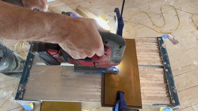 A jigsaw cuts a board. A top-down view, medium shot. A jigsaw in the hands of a craftsman. Interior renovation. Interior restoration and refurbishment. Home improvement.