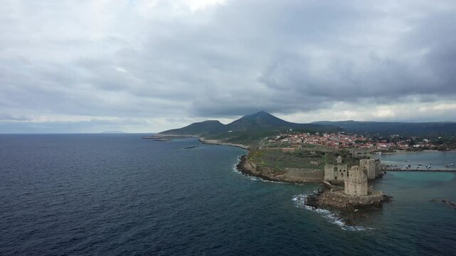 Aerial view of Methoni Castle overlooking the sea and the town of Methoni, Greece, under a dramatic cloudy sky.