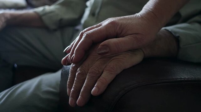 Senior woman putting her hand on her husbands while sharing moments of bonding. Affectionate elderly married couple having bonding moments together.