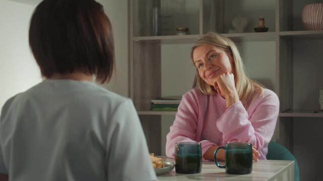white woman receiving microcurrent facial consultation, calm clinical studio, esthetician explaining handheld device, ceramic mugs on table, soft natural light, gentle smile, relaxed posture, visible
