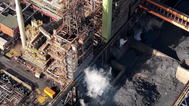 Close up aerial drone view of industrial coking units and dark petroleum coke piles for energy generation at Immingham refinery UK