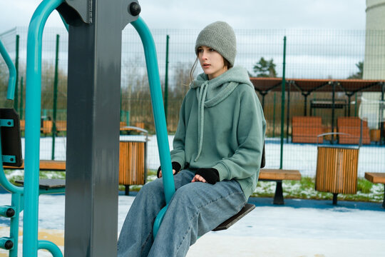 A teenager working out on a leg press machine outdoors. Daily routine of maintaining physical health and activity, focusing on strength and endurance.