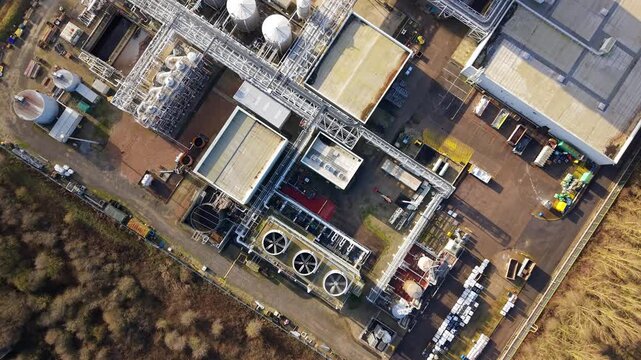 Top-down aerial drone view of a large-scale industrial factory in Grimsby, UK, featuring spinning turbine fans and complex pipework infrastructure.