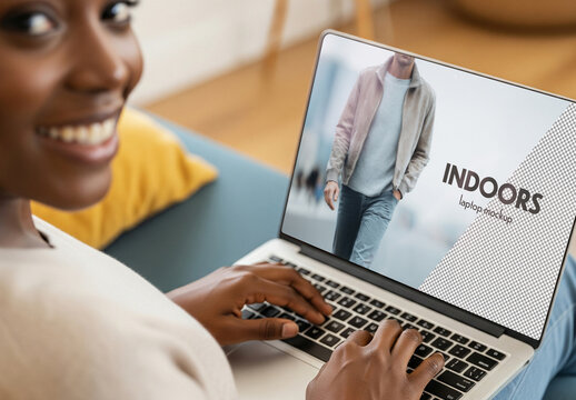 Closeup laptop mockup of black woman using laptop at home on sofa, looking back towards camera