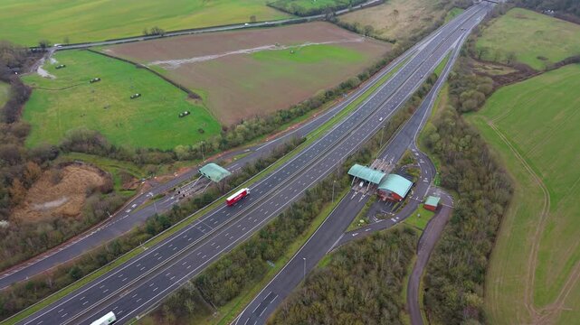 Aerial drone view of the M6 Toll motorway and its automated payment booths, with HGVs and commuter vehicles passing through near Birmingham, UK.