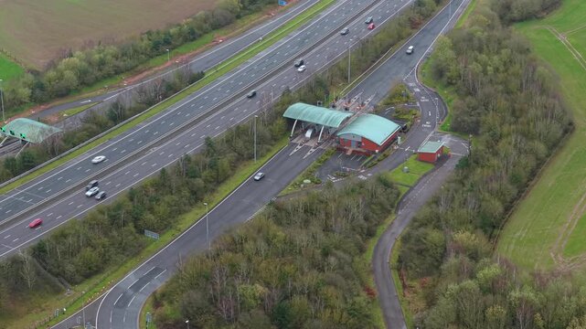 Aerial drone view of the M6 Toll motorway and its automated payment booths, with HGVs and commuter vehicles passing through near Birmingham, UK.