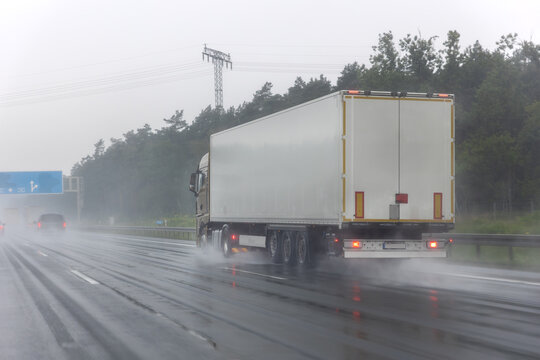 Close-up semi-trailer truck wheel driving fast Splashing Water on Highway, Risk of Aquaplaning on Wet Road. Detail view of hydroplane danger on rainy asphalt surface. Bad dangerous weather conditions