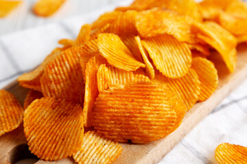 Paprika Flavored Crinkle Potato Chips on a Wooden Board, side view. Close-up.