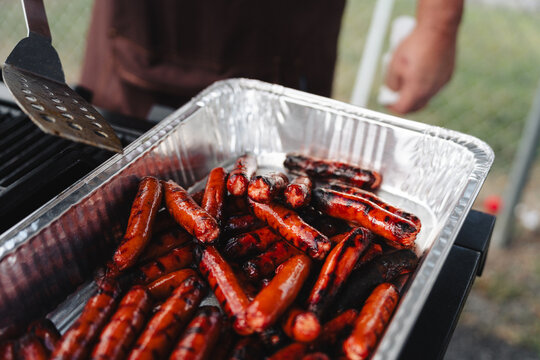 Grilled sausages in aluminum tray at backyard barbecue