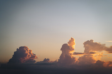 Towering cumulus clouds illuminated by orange sunset light