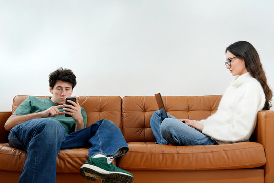 Young couple using digital devices ignoring each other