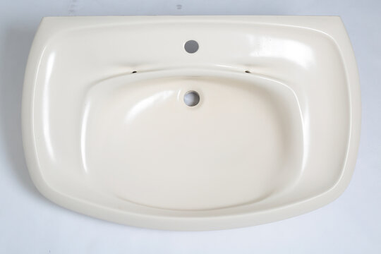 Clean, modern beige bathroom sink with two faucet holes on a white background
