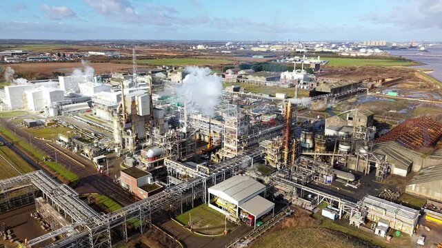 Aerial drone view of heavy industry petrochemical refinery with smoking chimneys and intricate pipework in Immingham UK at sunset