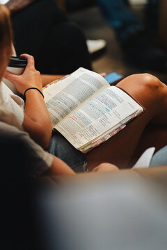 Woman reading bible with highlighted text and coffee cup
