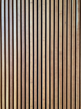 Close up of vertical wooden slats with natural grain and warm tones, creating a clean geometric pattern and minimalist background