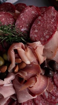 Top view close up of premium charcuterie board with prosciutto, ham, pancetta, bondiola, salami, longaniza, olives and almonds for elegant event catering