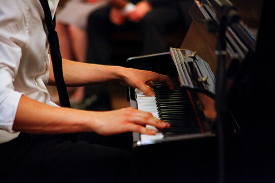 Close-up of a musician's hands playing a grand piano during a performance