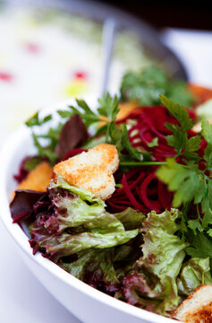 Freshly prepared beet and lettuce salad with croutons and parsley garnish