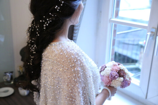 Elegant bride with pearl-adorned hair accessory and sequined shawl holding a bouquet
