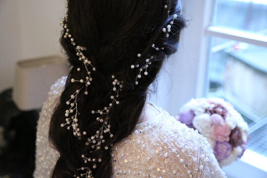 Elegant bride's braided hairstyle adorned with delicate pearl and crystal hair vine