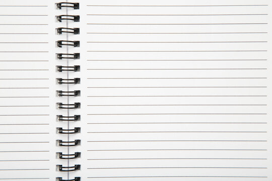Macro shot of a black metal double-wire spiral binding on white notebook.
