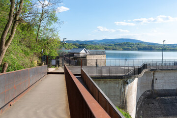 Dobczyce Castle and Dobczyce Dam, Poland &ndash; April 20, 2025: Metal pedestrian walkway leading toward Dobczyce Dam above Dobczyce Reservoir. Concrete structure, railing and calm water surface highlight m