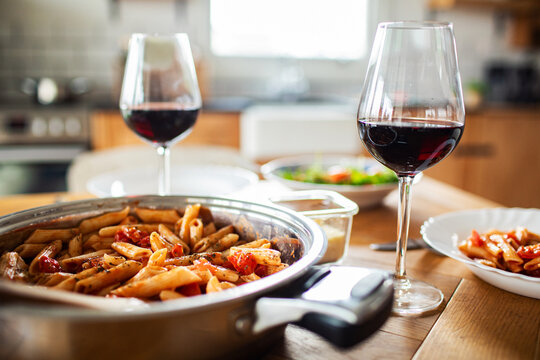 Red wine and penne pasta dinner in a cozy home kitchen