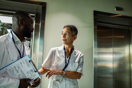 Medical professionals discussing patient chart in hospital corridor