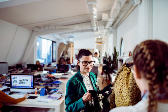 Two fashion designers reviewing garments in creative office