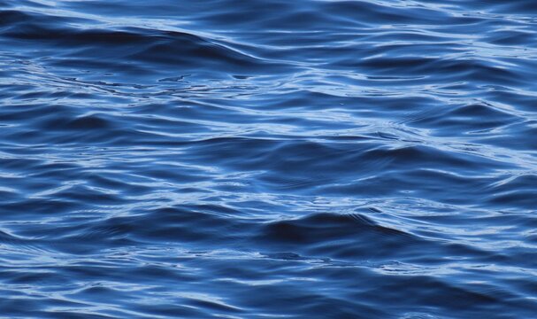 Bright blue water surface with soft waves as a background
