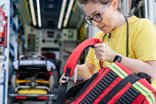 Paramedic preparing medical bag in ambulance: emergency service
