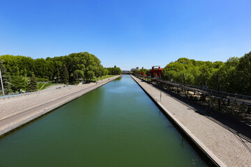 Fototapeta premium City canal waterway in summer park straight city canal view
