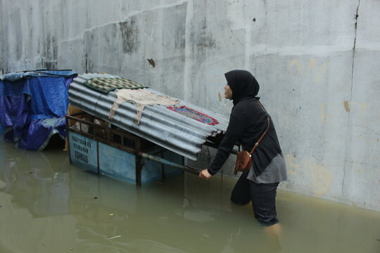 asian woman walking across flooding street